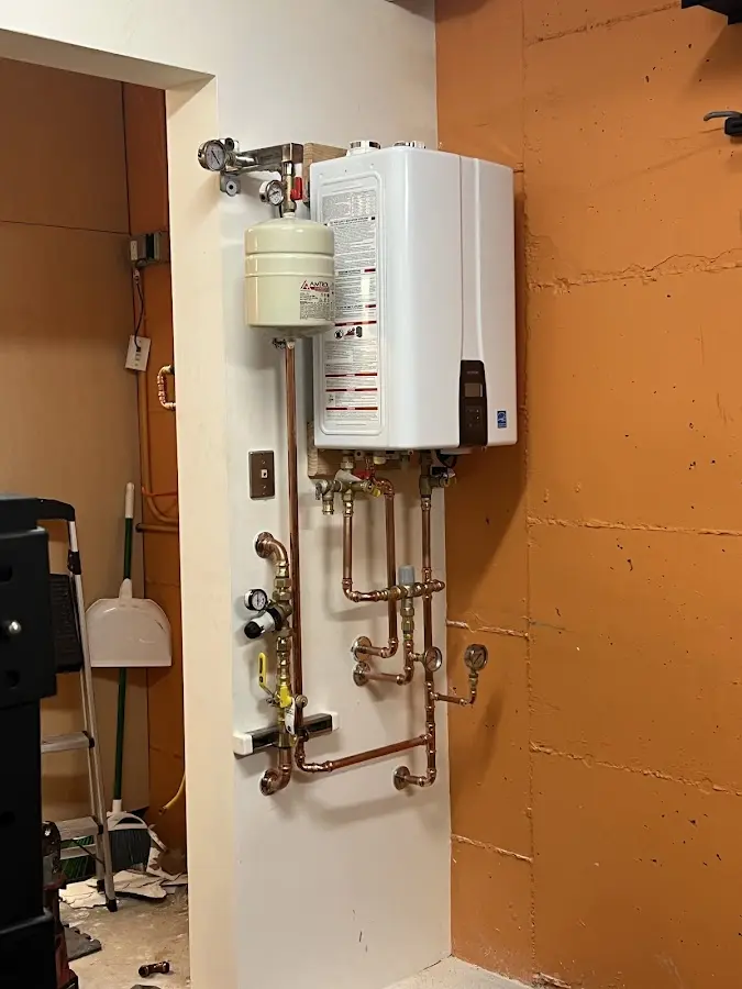 Plumbing technician inspecting water heater connections in Wake Forest